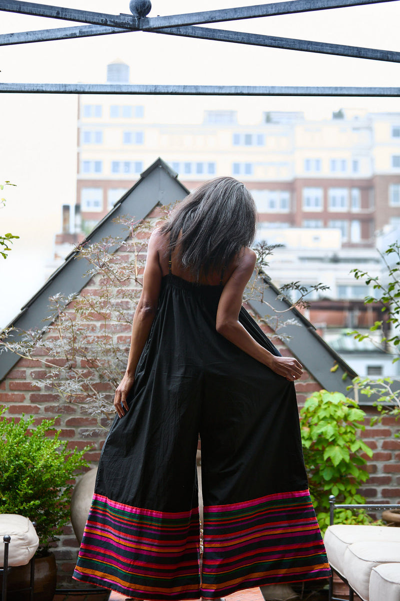 Person wearing a black dress with colorful trim on a rooftop with cityscape view